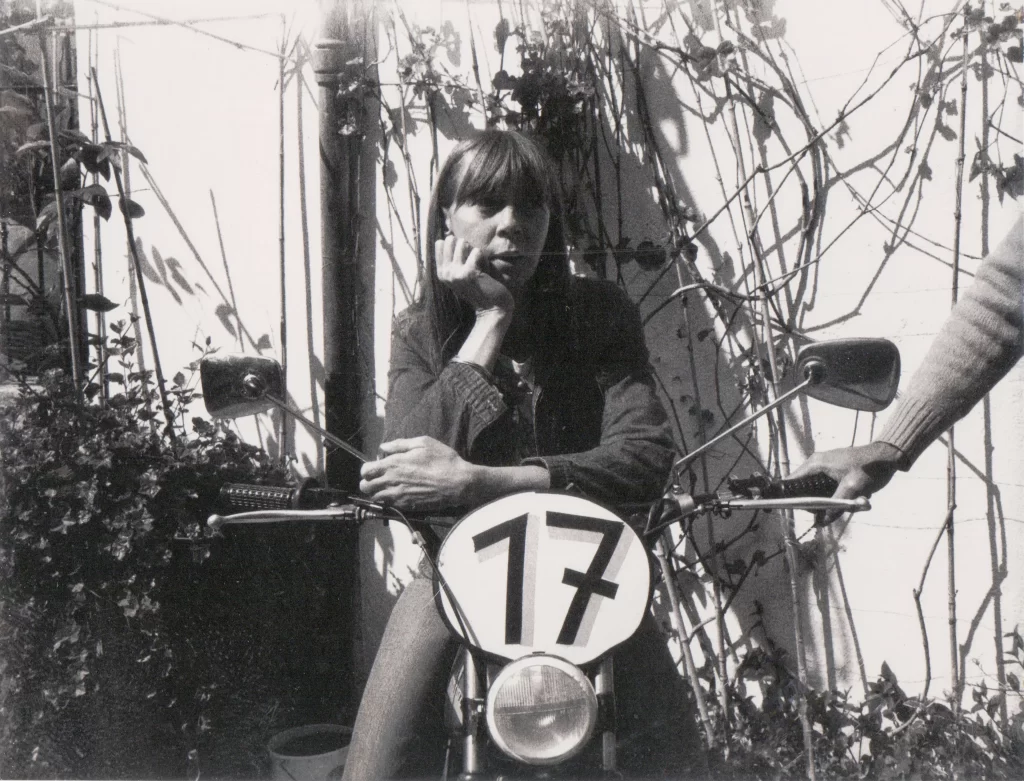 Black and white photo of a young woman on a motorbike