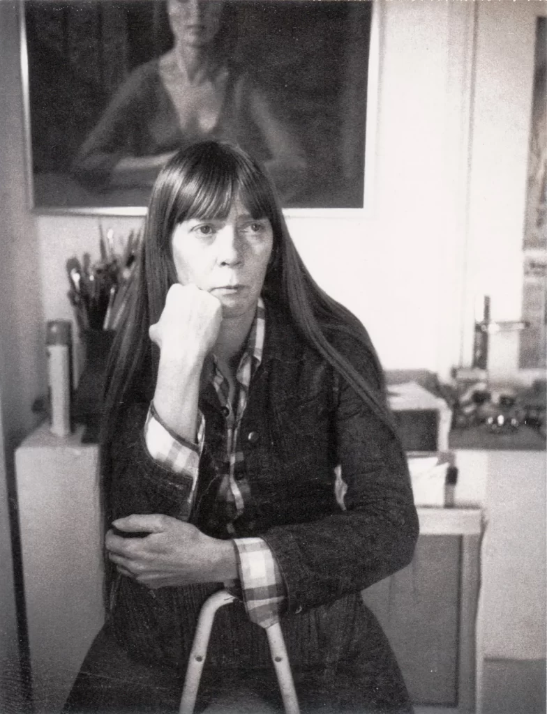 Black and white photo of a young woman sitting backwards on a chair