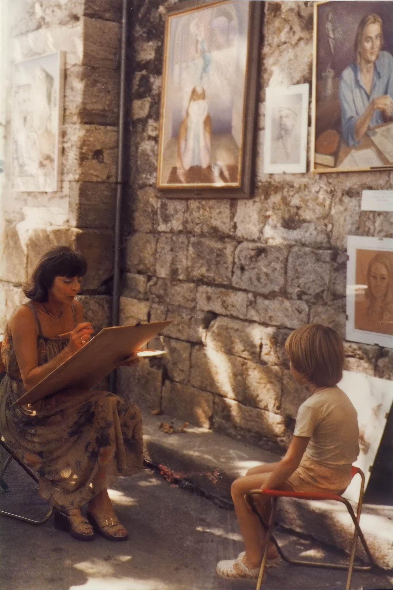 Photograph of the artist doing a sketch of a young boy at a street fair.